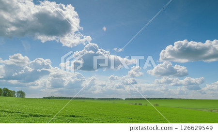 Expansive Lush Green Fields Stretching Under a Bright Blue Sky Filled with Fluffy White Clouds Time lapse. Expansive Lush Green Fields Stretching Under a Bright Blue Sky Filled with Fluffy White Clouds Time lapse. 126629549
