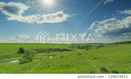 A Vibrant Green Landscape bathed in Warm Sunlight, with a Beautiful Cloudy Sky above Time lapse. A Vibrant Green Landscape bathed in Warm Sunlight, with a Beautiful Cloudy Sky above Time lapse. 126629652