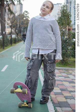 Smiling young girl child in casual with skateboard outdoors Smiling young girl child in casual with skateboard outdoors 126629769