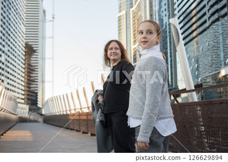 Friendly woman and young girl child walking along the streets of the city.  126629894