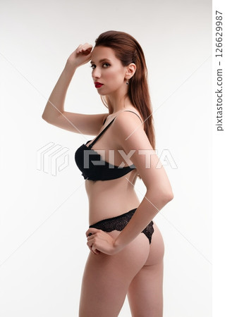 Elegant woman in lingerie poses gracefully in a studio setting 126629987