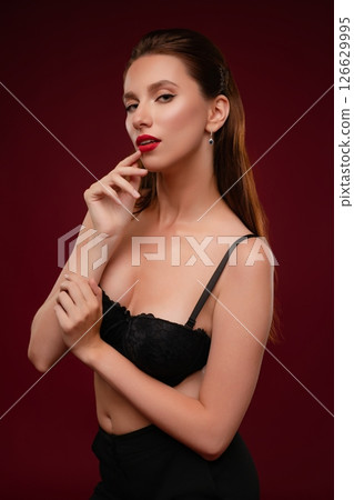 Captivating woman posing in elegant lingerie against a rich backdrop 126629995