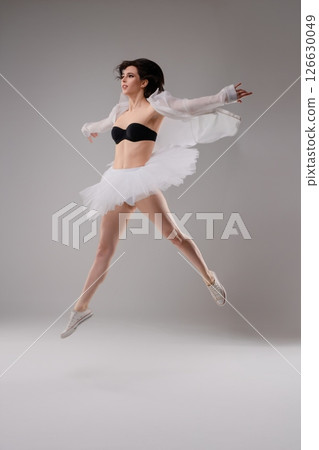 Woman in lingerie performs a graceful ballet leap in a dance studio setting Woman in lingerie performs a graceful ballet leap in a dance studio setting 126630049