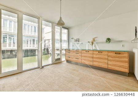 Bright and airy room featuring large windows, wooden cabinets, and a serene view of the water, promoting a calm and inviting atmosphere. 126630448