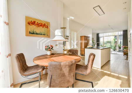A bright and inviting dining area featuring a wooden table, comfortable chairs, and colorful artwork, creating a warm and welcoming atmosphere. 126630470