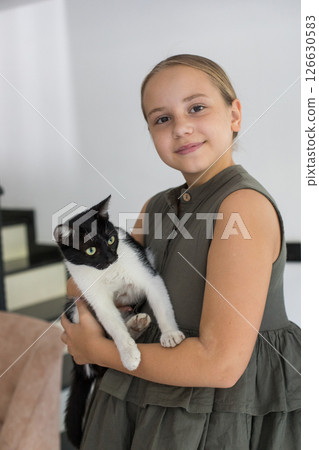 Attractive young girl hugging her cat pet sitting on cosy sofa, relaxing at home. Attractive young girl hugging her cat pet sitting on cosy sofa, relaxing at home. 126630583