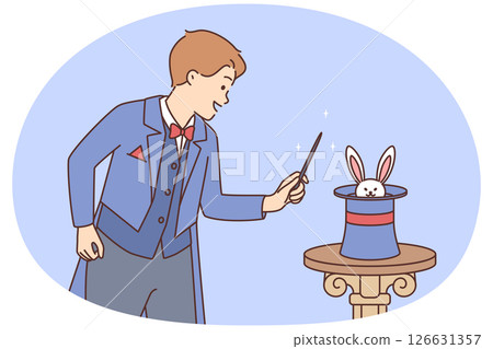 Man magician stands near hat in which rabbit is hiding in preparation for stunt 126631357
