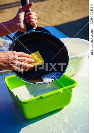 Woman washing dishes in bowl, capming outdoor 126631689