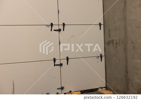 Wall leveling system. Instalation of ceramic tile in a bathroom on plastered walls. 126632192