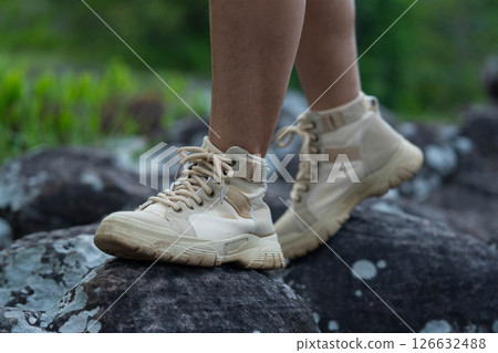 Close-up of the legs of a female hiker walking on a mountain trail. 126632488
