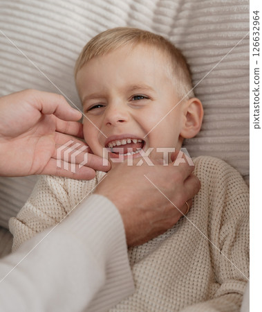 Close-up of a 4-year-old boy's face laughing from tickling his dad at home on the couch. High quality photo 126632964