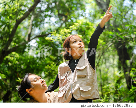 Asian mother takes her daughter to learn about nature in the forest to explore nature from the real place. Mother and daughter are enjoying nature outdoors, adventuring in the forest. Asian mother takes her daughter to learn about nature in the forest to explore nature from the real place. Mother and daughter are enjoying nature outdoors, adventuring in the forest. 126632983