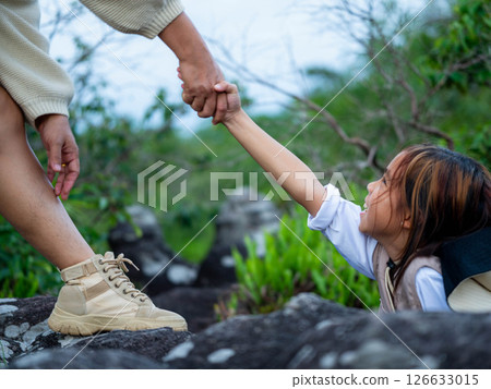 Family team success. Mother and daughter hike together in the mountains during spring vacation. Helping hand in teamwork. 126633015