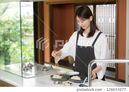 A woman wearing an apron preparing a meal 126633077