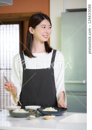 A woman wearing an apron preparing a meal 126633086