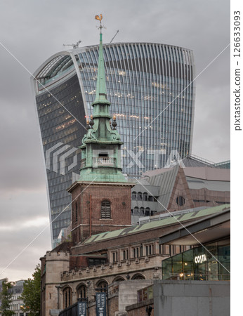 The copper green spire steeple of All Hallows by the Tower church (Ancient Anglican church) in front of The modern 20 Fenchurch Street (Walkie-Talkie building). The copper green spire steeple of All Hallows by the Tower church (Ancient Anglican church) in front of The modern 20 Fenchurch Street (Walkie-Talkie building). 126633093