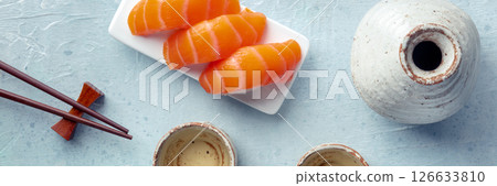 Sake and ochoko, traditional cup, with salmon sashimi and chopsticks Sake and ochoko, traditional cup, with salmon sashimi and chopsticks 126633810
