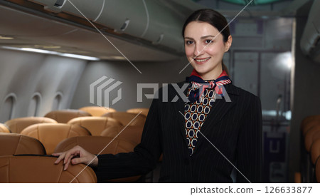 Flight attendant or Air Hostess. A friendly flight attendant stand confidently inside an airplane cabin. Professional hospitality and elegant uniform. Aviation service travel airline Flight attendant. Flight attendant or Air Hostess. A friendly flight attendant stand confidently inside an airplane cabin. Professional hospitality and elegant uniform. Aviation service travel airline Flight attendant. 126633877