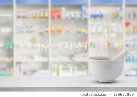 Mortar and pestle on pharmacy counter top with blur medicine shelves in drugstore background Mortar and pestle on pharmacy counter top with blur medicine shelves in drugstore background 126633899