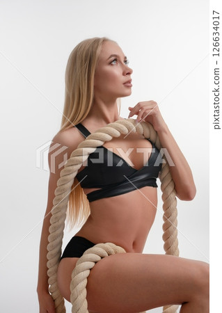 Woman displaying beauty and strength in a sport studio setting with rope 126634017