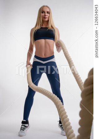 Woman showcasing fitness skills in a studio setting with battle ropes Woman showcasing fitness skills in a studio setting with battle ropes 126634043