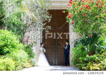 Bride and groom standing in front of a church 126634239