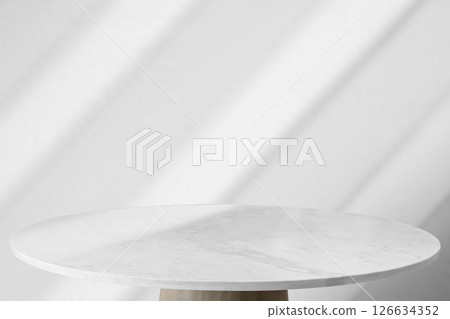 Round marble table top with abstract shadow drop on white wall background for mockup product display 126634352
