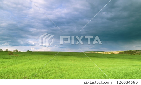 A Vast Green Field Spreads Out Beneath a Dramatic and Beautiful Cloudy Sky Above Time lapse. A Vast Green Field Spreads Out Beneath a Dramatic and Beautiful Cloudy Sky Above Time lapse. 126634569