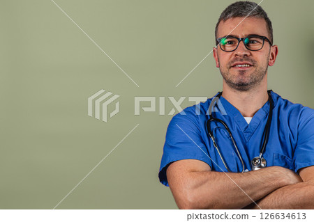 Doctor in blue scrubs with stethoscope smiling confidently in studio Doctor in blue scrubs with stethoscope smiling confidently in studio 126634613