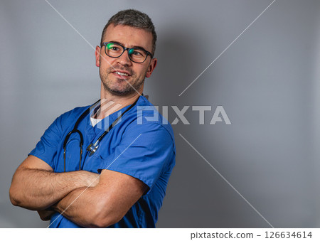 Smiling healthcare professional wearing scrubs and glasses poses confidently Smiling healthcare professional wearing scrubs and glasses poses confidently 126634614