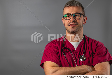 Medical professional wearing scrubs and glasses poses confidently in clinic Medical professional wearing scrubs and glasses poses confidently in clinic 126634623
