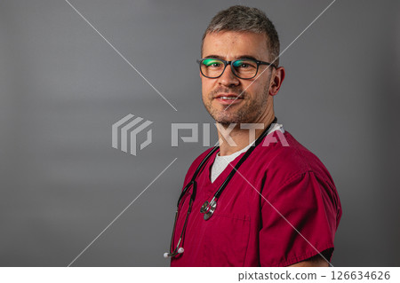 Caring healthcare professional in scrubs with a stethoscope in a studio 126634626