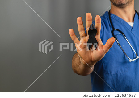 Healthcare worker holding a black ribbon to honor those affected by loss 126634658