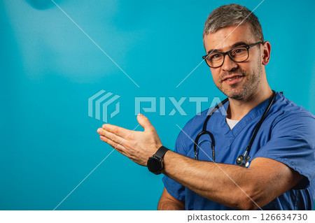 Healthcare professional in scrubs gestures toward a bright background 126634730