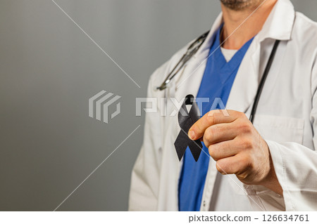 Healthcare worker holding a black ribbon in support of a cause Healthcare worker holding a black ribbon in support of a cause 126634761