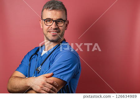 Young medical professional smiling against a pink background Young medical professional smiling against a pink background 126634989