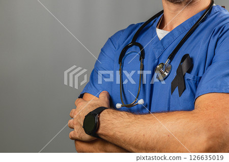 Healthcare worker in blue uniform with black ribbon at memorial 126635019
