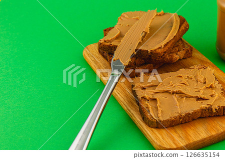 Creamy peanut butter spread on whole grain bread slices 126635154
