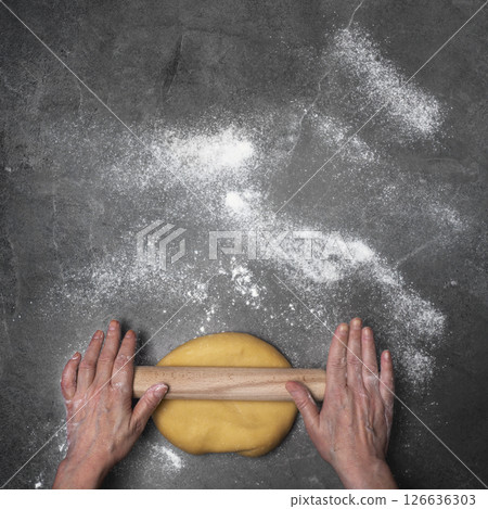 Caucasian hands rolling dough on floured board flat lay view with copy-space 126636303