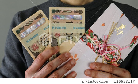 一個人拿著一疊鈔票和一個禮物信封 一個人拿著一疊鈔票和一個禮物信封 126638117