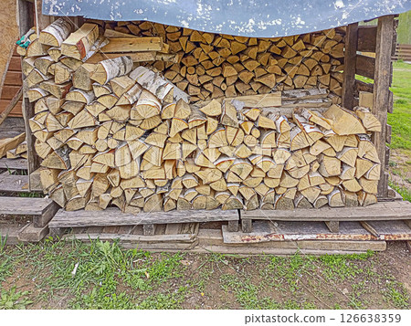 Rows of split firewood, birch wood, laid out in rows for drying. Use of renewable energy for heating the home, cooking in the absence of access to electricity, gas, oil. An attribute of rural life Rows of split firewood, birch wood, laid out in rows for drying. Use of renewable energy for heating the home, cooking in the absence of access to electricity, gas, oil. An attribute of rural life 126638359