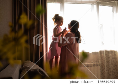 Close-up of mother and daughter exchanging loving whispers and giggles. Perfect illustration of secure attachment and childhood happiness. Close-up of mother and daughter exchanging loving whispers and giggles. Perfect illustration of secure attachment and childhood happiness. 126639295
