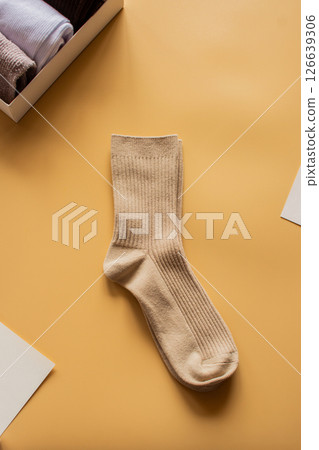 Elegant neutral-toned socks against a bright yellow backdrop. Ideal for lifestyle, clothing brands, or cozy autumn concepts. Vertical flat lay. Elegant neutral-toned socks against a bright yellow backdrop. Ideal for lifestyle, clothing brands, or cozy autumn concepts. Vertical flat lay. 126639306
