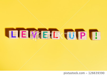 Colorful Level Up text on wooden blocks over bright yellow background 126639390