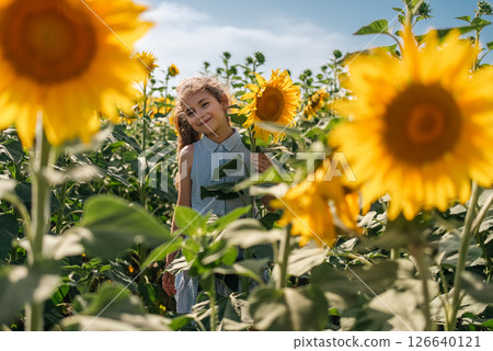 Beautiful little girl in yellow garden of sunflowers. Beautiful little girl in yellow garden of sunflowers. 126640121