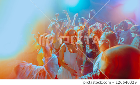 Vibrant party scene with people dancing under colorful lights. 126640329