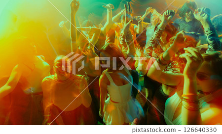 Vibrant nightclub scene with diverse crowd dancing energetically, colorful lights. 126640330