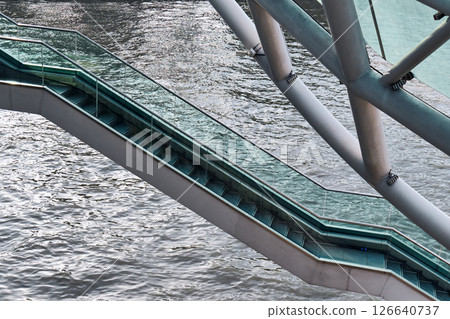 Modern pedestrian bridge spans over flowing river. High quality photo Modern pedestrian bridge spans over flowing river. High quality photo 126640737
