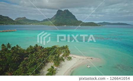 Turquoise lagoon water gently laps the idyllic white sand beach of Bora Bora, with mount Otemanu majestically rising in the background, creating a breathtaking tropical paradise 126641054