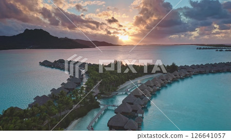 Luxury resort overwater bungalows, Bora Bora, French Polynesia. Amazing colorful sunset sky over hotel luxury villas coral reef lagoon. Wild nature paradise, exotic summer travel. Aerial drone flight 126641057